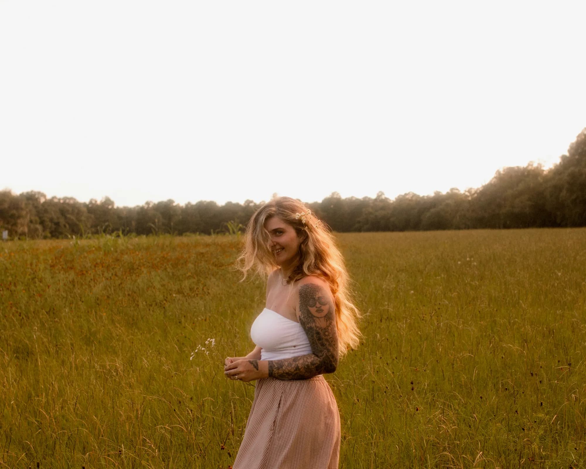 Mckenzie standing in a sunlit wildflower field